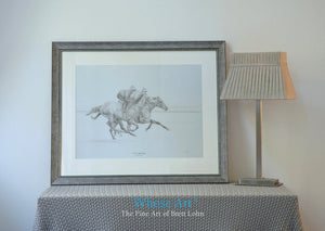 Black and white horse print framed in silver, showing two horses galloping with jockeys on board. The lead horse is a grey.