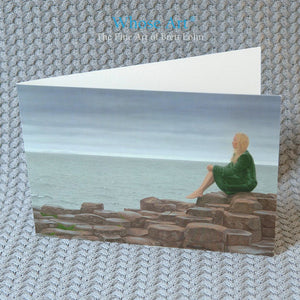 Fine art card of a painting depicting the Giant's Causeway & a young lady in a green velvet coat sitting on the stones
