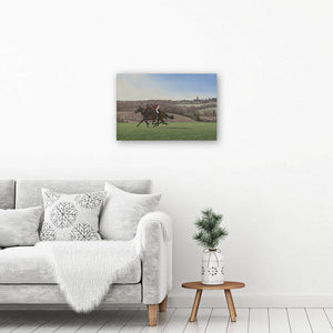 Galloping horses art print of a painting of two horses on the gallops in the morning. Picture hangs above a table & armchair.