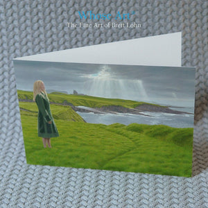 Irish art card of a painting of a lady in Mullaghmore standing in front of a County Sligo castle. The card stands on a table.