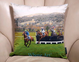 velour cushion cover featuring a painting of horses racing at cheltenham, placed on a leather armchair