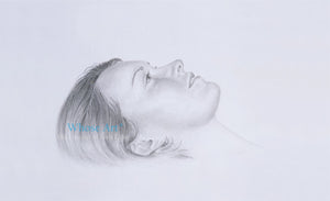 Black and white wall art drawing showing the face of a girl, shaded in pencil, lying down but looking upwards, daydreaming.
