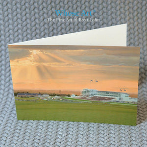 Derby art card with a horse art painting of horse racing at epsom downs racecourse on the front. The card sits on a table. 