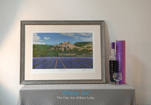 Framed wall art picture of lavender fields surrounding an old stone village on a hill in the sunny South of France. 