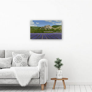 Lavender landscape art canvas print showing a painting of a village amid lavender fields in Provence. Canvas hangs by a chair