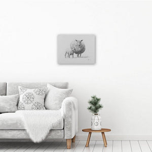 Sheep art canvas print hanging on a white wall above an armchair and a table with a plant on it. Canvas art print of a lamb.