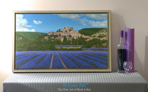Wall Art Canvas print of a painting of Lavender Fields with an old French village on a hill in their midst. Framed in Gold